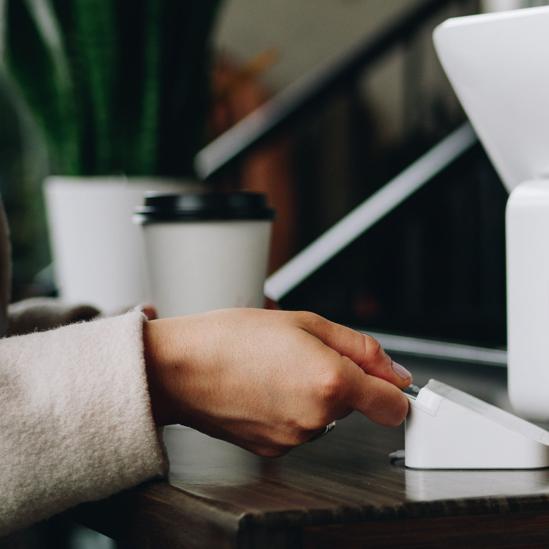 Woman with white sleeve uses her secure Visa card to pay for coffee